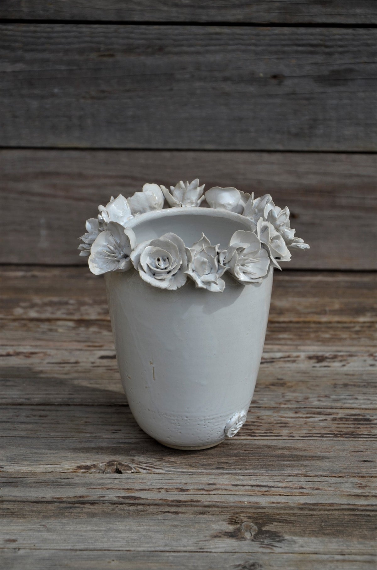 Vaso alto bianco in gres con una corolla di fiori misti sulla sommità