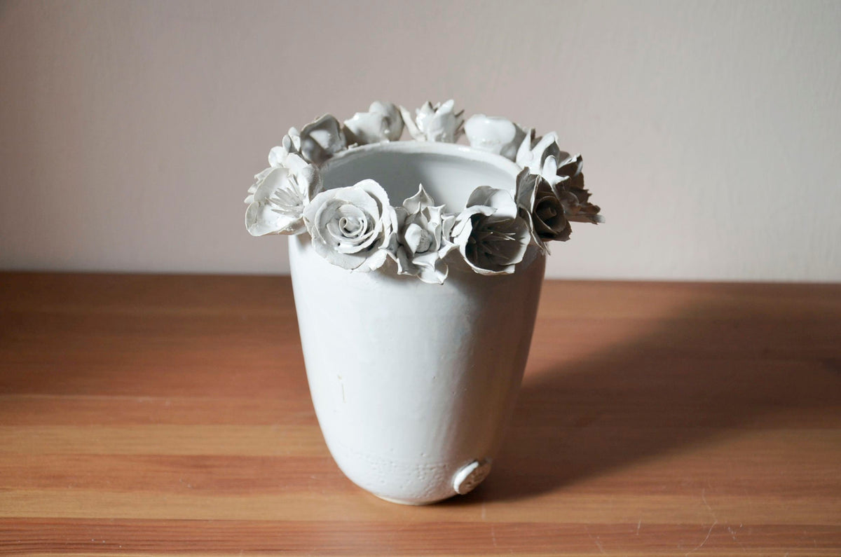 Vaso alto bianco in gres con una corolla di fiori misti sulla sommità