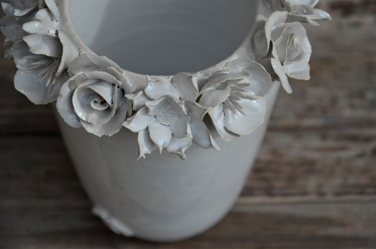 Vaso alto bianco in gres con una corolla di fiori misti sulla sommità